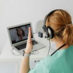 A female doctor engaged in a video call consultation with a patient on a laptop.